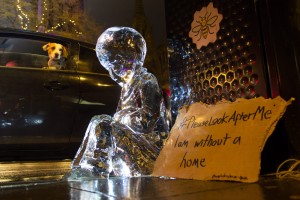 Dog looking on at the ice sculpture of a child in Manchester to raise awareness of homelessness