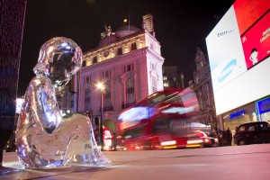 The final ice sculpture No.7 by the bright lights of Piccadilly Circus, with a bus rushing past. #pleaselookafterme
