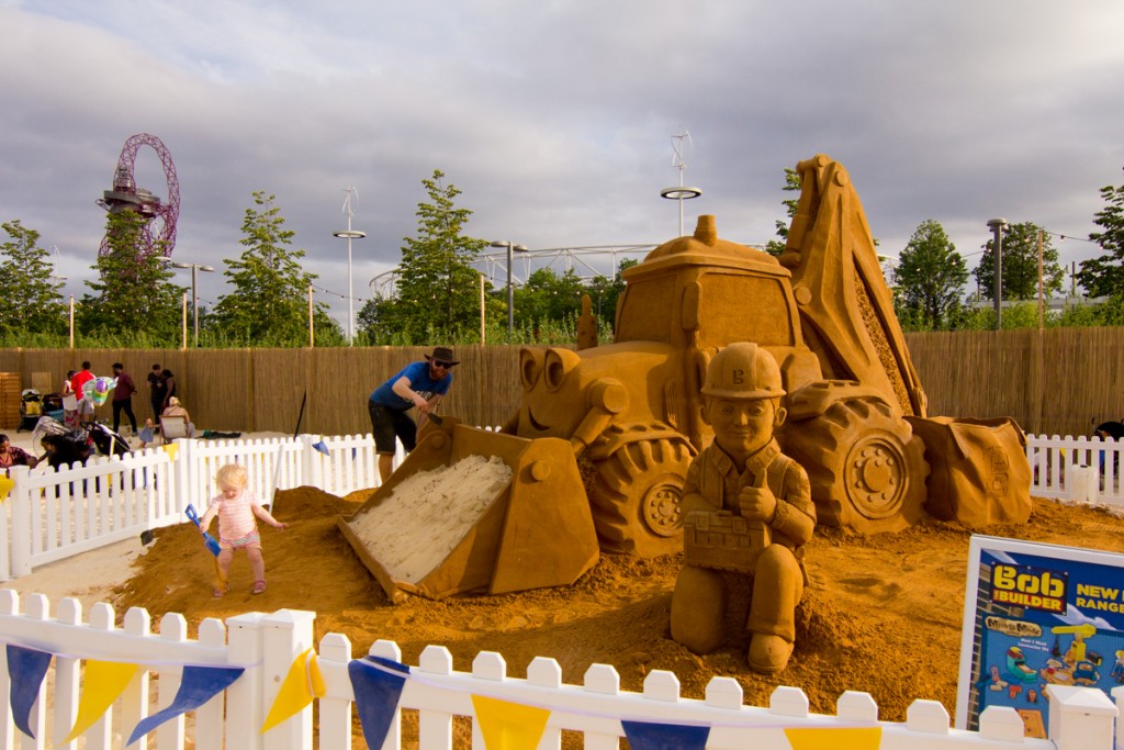 UK sand sculptor Jamie Wardley poses with the giant Bob The Builder sand sculpture at an urban beach at Olympic Park London