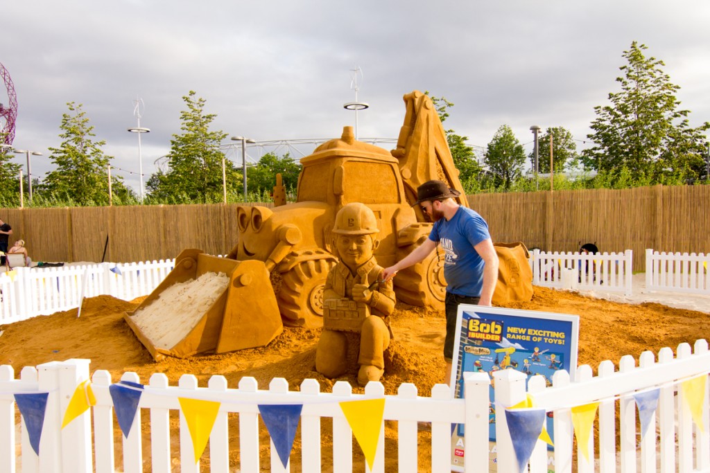 UK sand sculptor Jamie Wardley poses with the giant Bob The Builder sand sculpture at an urban beach at Olympic Park London